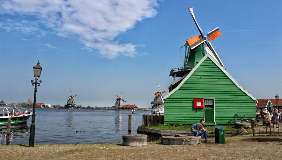 Serene landscape featuring iconic Dutch windmills by a tranquil waterfront under a clear sky.