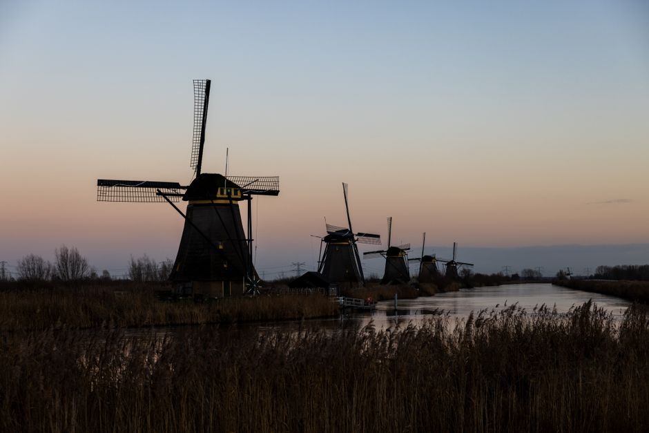 Captivating sunset view of iconic Kinderdijk windmills reflecting on the waterway.